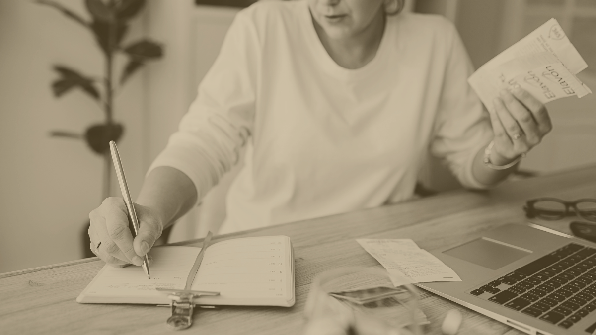 Travailleuse indépendante organisant ses justificatifs et dépenses professionnelles sur un bureau avec ordinateur portable et carnet de suivi.